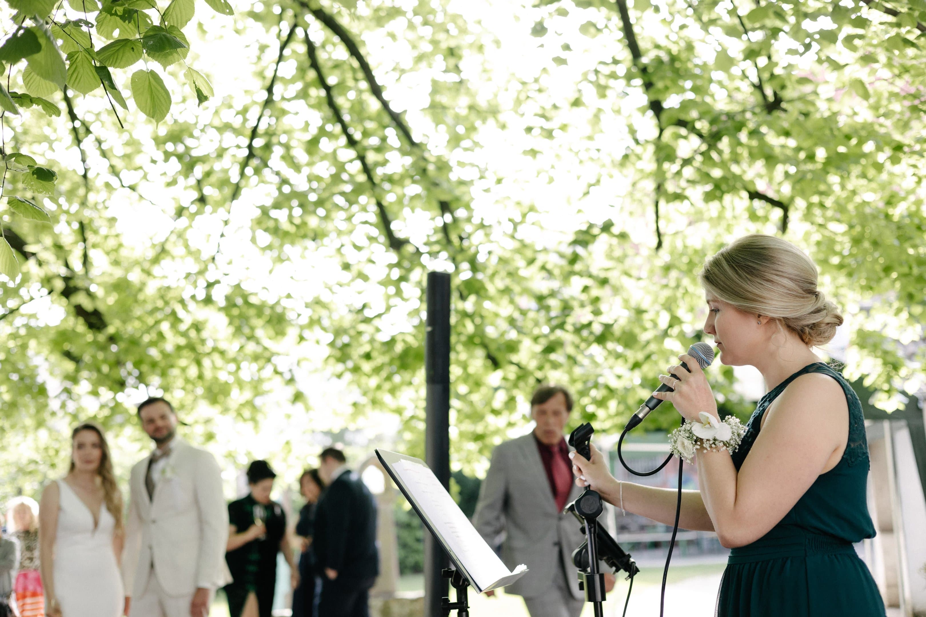 Tanja Schroers singt bei einer Trauung im Freien, im Hintergrund das Brautpaar